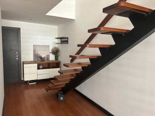 a staircase in a living room with white walls at Amplio Loft Duplex sector hotelero y financiero de Quito in Quito