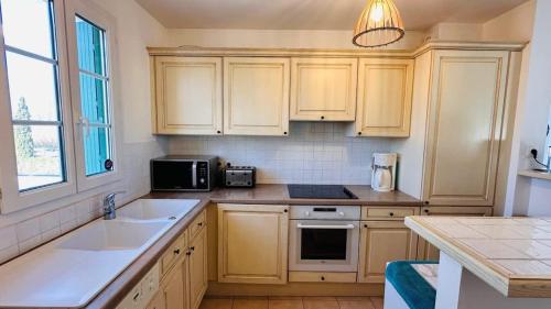 La cuisine est équipée de placards en bois, d'un évier et d'un four micro-ondes. dans l'établissement Seabird Appartement Lumineux Port Grimaud, à Grimaud