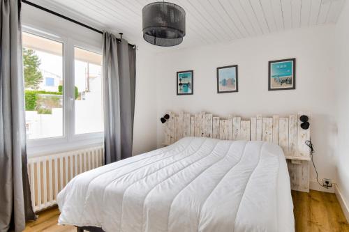 a bedroom with a white bed and a window at Maison à Barbâtre pour 10 - 450m de la plage in Barbâtre
