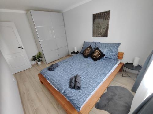 a bedroom with a blue bed with shoes on it at Becky Apartman in Komló