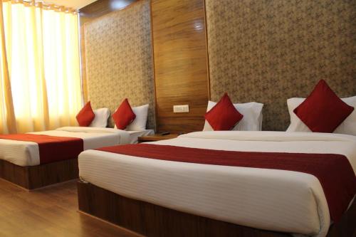 a hotel room with two beds with red pillows at Black Diamond Hotel & Spa in Zirakpur