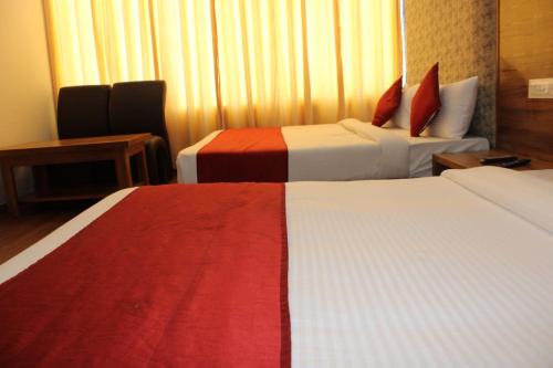 a hotel room with two beds with red and white at Black Diamond Hotel & Spa in Zirakpur