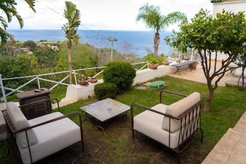 a patio with chairs and a grill and the ocean at Villa Zagara Garden Spectacular Sea View in Taormina in Taormina