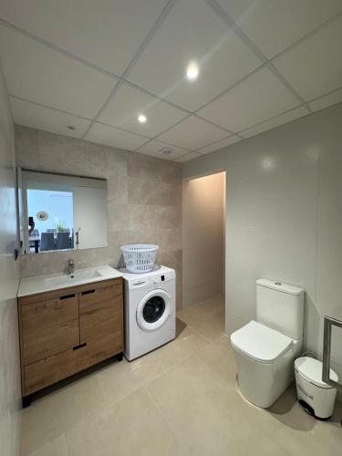 a bathroom with a washing machine and a toilet at Caseta De L'avi in Camarles