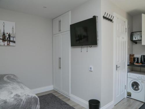 a bedroom with white cabinets and a tv on the wall at StayZo - Crofton Park - Central London refurbished Studio in London