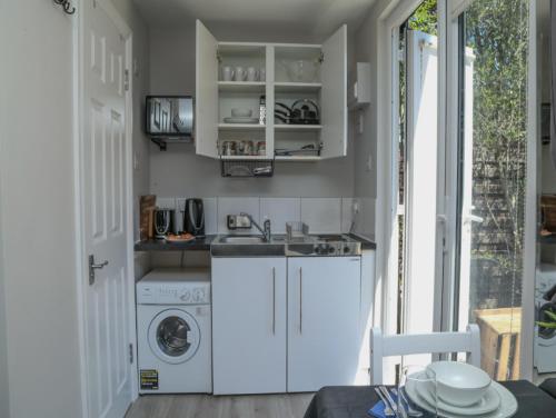 a kitchen with a sink and a washing machine at StayZo - Crofton Park - Central London refurbished Studio in London
