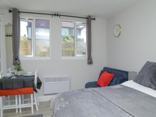 a bedroom with a bed and a table and windows at StayZo - Crofton Park - Central London refurbished Studio in London