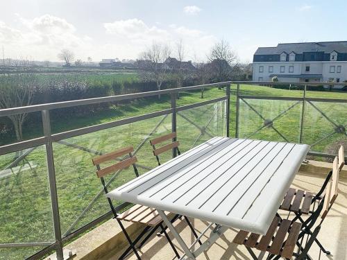 una mesa blanca y sillas en un balcón con un campo en Terrasse de l'aber Roscoff, en Roscoff