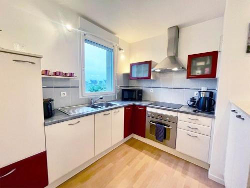 une cuisine avec des armoires blanches, un évier et une fenêtre dans l'établissement Terrasse de l'aber Roscoff, à Roscoff