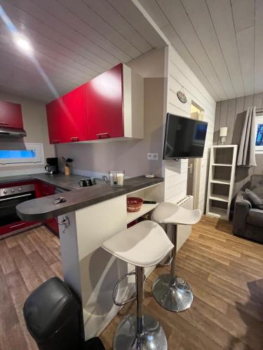 una cucina con 2 sgabelli da bar e una cucina con armadi rossi di Joli chalet, jardin clos, terrasse, 2chambres a Saint-Germain-sur-Ay