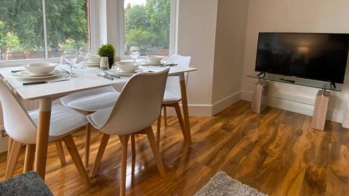 a dining room with a table with chairs and a television at De Parys Premier Lodge 3 in Bedford in Bedford