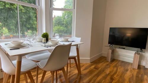 a dining room with a table with chairs and a television at De Parys Premier Lodge 3 in Bedford in Bedford