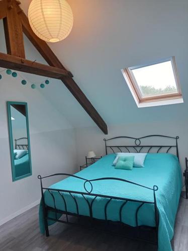 une chambre avec un lit avec des draps bleus et une fenêtre dans l'établissement Les Gîtes du Triskell, Gîte de l'AIR, à Sainte-Tréphine