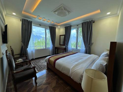Un dormitorio con una cama y una silla y ventanas. en Relax Inn Skardu, en Skardu