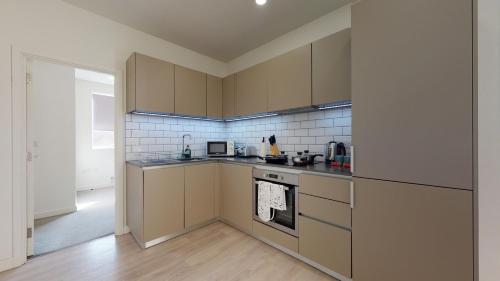 a kitchen with stainless steel appliances and brown cabinets at Luxury Apartment - Town Centre North Stevenage in Stevenage