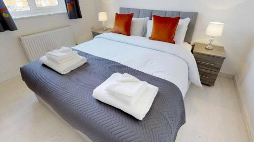 a bedroom with a large bed with towels on it at StayZo Cole Green Lane Accommodation- FREE Parking in Welwyn Garden City