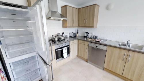 a kitchen with wooden cabinets and stainless steel appliances at StayZo Cole Green Lane Accommodation- FREE Parking in Welwyn Garden City