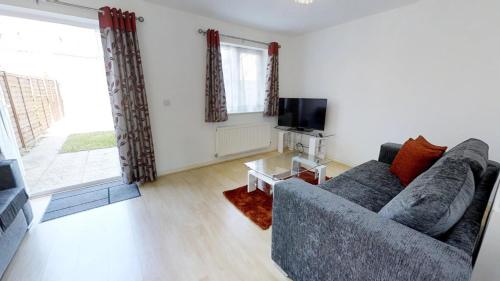 a living room with a couch and a tv at StayZo Cole Green Lane Accommodation- FREE Parking in Welwyn Garden City