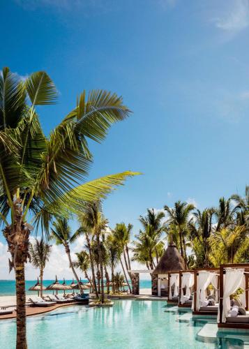 a pool at the beach with palm trees and chairs at One&Only Le Saint Géran, Mauritius in Belle Mare