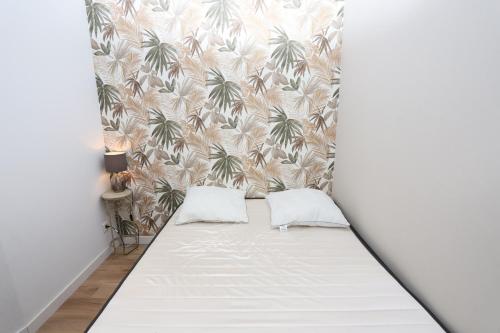 un lit dans une chambre avec un papier peint avec des palmiers dans l'établissement Appart refait a neuf st Cyprien, à Saint-Cyprien