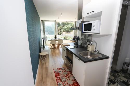 une petite cuisine avec un évier et un micro-ondes dans l'établissement Appart refait a neuf st Cyprien, à Saint-Cyprien