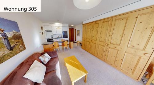 a room with a couch and a table and a kitchen at Schweizerhaus Apartments in Maloja