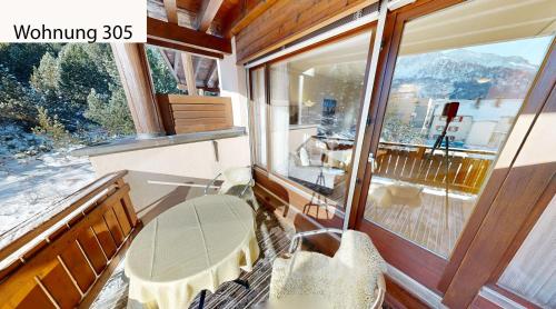 a room with a balcony with a large window at Schweizerhaus Apartments in Maloja
