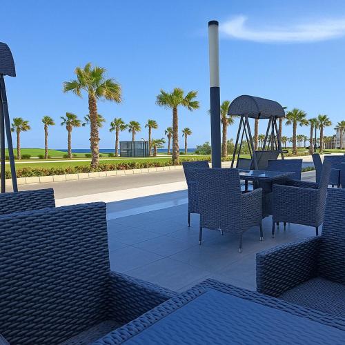 a patio with chairs and a table and palm trees at Private Chalet with Relaxing Outdoor Area in Port Said