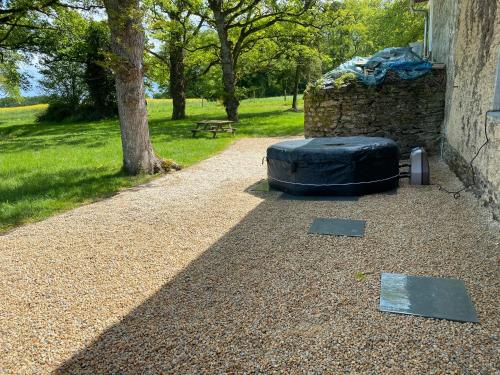 a gravel path with a rock wall and a tree at Maison de campagne Rennes Parc Expo in Mordelles