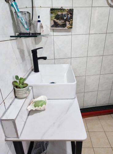 a white sink in a white tiled bathroom at Eternal Seaside House in Nangan