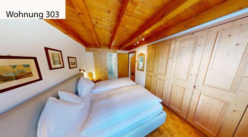 a bed in a room with a wooden ceiling at Schweizerhaus Apartments in Maloja