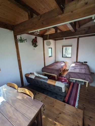 a room with three beds and a couch and tables at guest house antena ゲストハウスアンテナ in Minami Aso