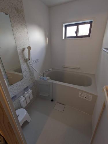 a bathroom with a tub and a sink and a mirror at guest house antena ゲストハウスアンテナ in Minami Aso