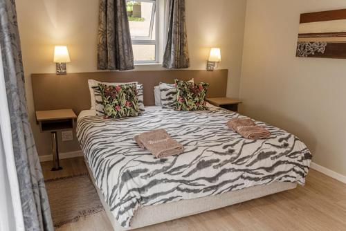 a bedroom with a large bed with a zebra print sheets at The Suites at Waterryk Eco Guest Farm in Stilbaai