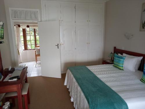 a bedroom with a bed and a desk and a door at Ocean Grove Guesthouse in Port Edward