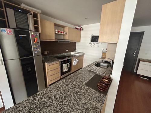 a kitchen with a stove and a refrigerator at Amplio Loft Duplex sector hotelero y financiero de Quito in Quito