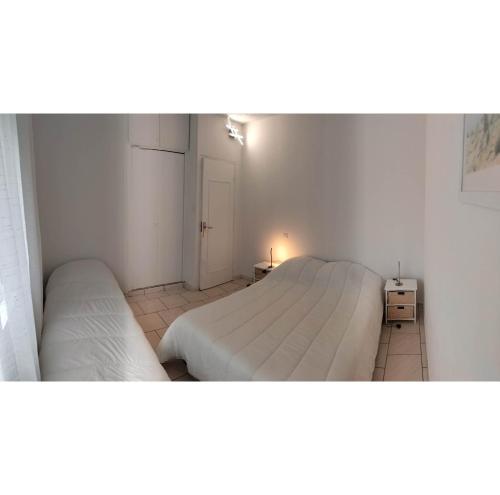 deux lits dans une petite pièce aux murs blancs dans l'établissement Villa entre mer et forêt, à Saint-Trojan-les-Bains