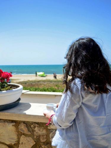 a little girl standing on a wall near the beach at Hotel Mar & Sol in Punta Secca