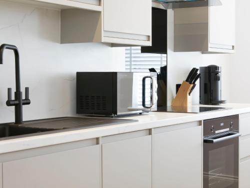 a kitchen with white cabinets and a black microwave at The Salisbury sleeps 4 Classic Apartment in Scarborough