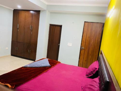 a bedroom with a bed with pink sheets and wooden cabinets at Hotel Elite Stay in Gurgaon