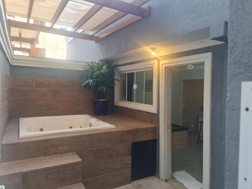 a bathroom with a tub and a potted plant at Marmeu Tombo com Hidro Aquecida Privativa in Guarujá