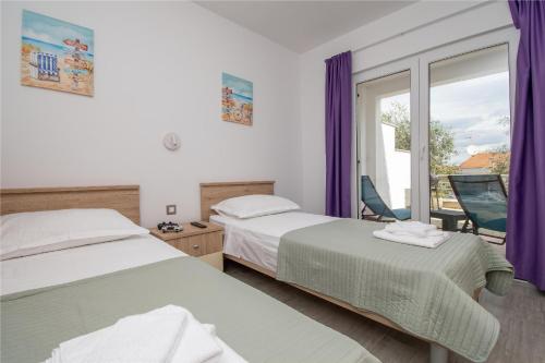 a hotel room with two beds and a window at Apartment MAYA in Nečujam