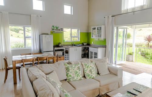 a living room with a white couch and a kitchen at The Suites at Waterryk Eco Guest Farm in Stilbaai