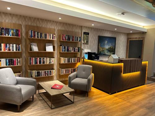 a library with two chairs and a table and shelves of books at Havana Apart Hotel in Alanya