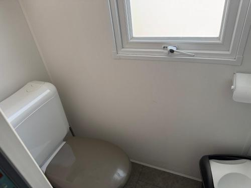 Un baño con inodoro blanco y ventana. en Mobil home propre et récent, en Argelès-sur-Mer