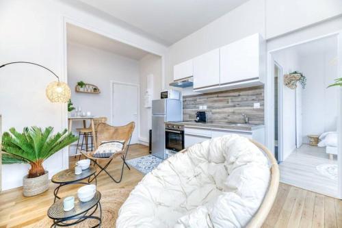 Il comprend un salon avec une chaise blanche et une cuisine. dans l'établissement T2 Prestige au cœur de Grenoble, à Grenoble