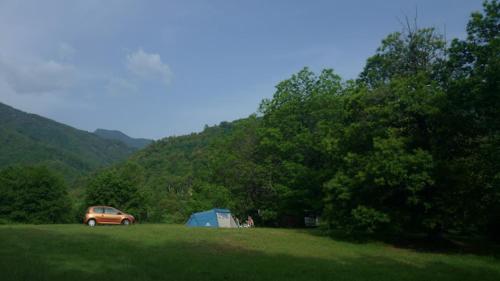 une voiture garée dans un champ à côté d'une tente dans l'établissement Camping Les Prairies, à Scata