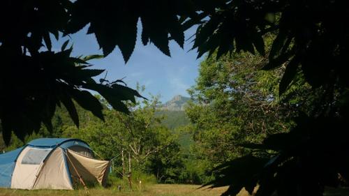 une tente bleue et blanche dans un champ arboré dans l'établissement Camping Les Prairies, à Scata