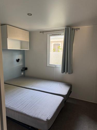 una cama en una habitación con ventana en Mobil home propre et récent, en Argelès-sur-Mer