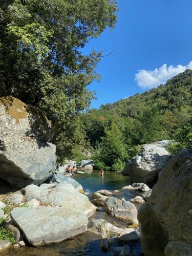 Un groupe de gens nageant dans une rivière avec des rochers dans l'établissement Camping Les Prairies, à Scata